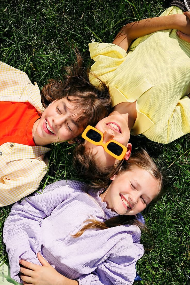 Children lying on grass smiling and enjoying outdoor playtime together